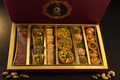 Gemischte Baklava-Geschenkbox mit Pistazien und Cashews, geöffnet, mit Nuss-Dekoration außerhalb der Box